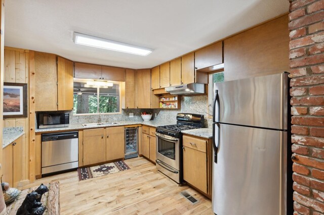 1167 Silver Tip Ln, Fish Camp, CA 93623 - kitchen featuring appliances with stainless steel finishes, beverage cooler, under cabinet range hood, light wood-style flooring, and decorative backsplash