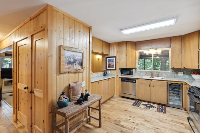 kitchen featuring stainless steel dishwasher, black microwave, beverage cooler, gas range oven, and a sink