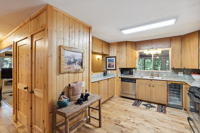 1167 Silver Tip Ln, Fish Camp, CA 93623 - kitchen featuring appliances with stainless steel finishes, wine cooler, light wood-style floors, backsplash, and wood walls