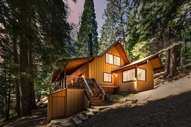 back of property with stairs, board and batten siding, and a deck