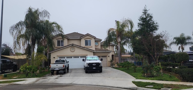 traditional-style home with fence, stucco siding, driveway, and a garage