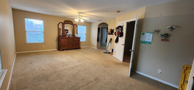 bedroom featuring baseboards, light carpet, a ceiling fan, and arched walkways