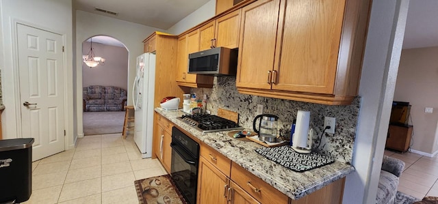kitchen with light stone countertops, stainless steel appliances, light tile patterned floors, tasteful backsplash, and visible vents