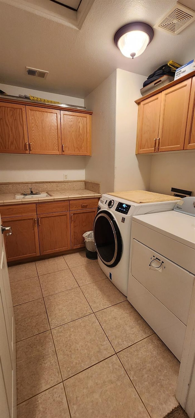 5360 E Heaton Ave, Fresno, CA 93727 - washroom featuring cabinet space, independent washer and dryer, light tile patterned floors, and a textured ceiling