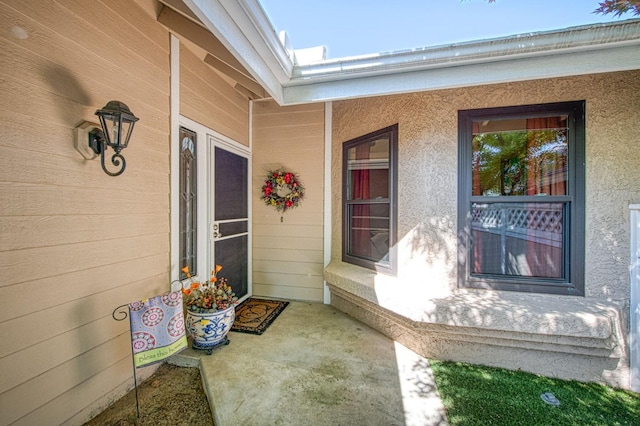view of exterior entry with a porch and stucco siding