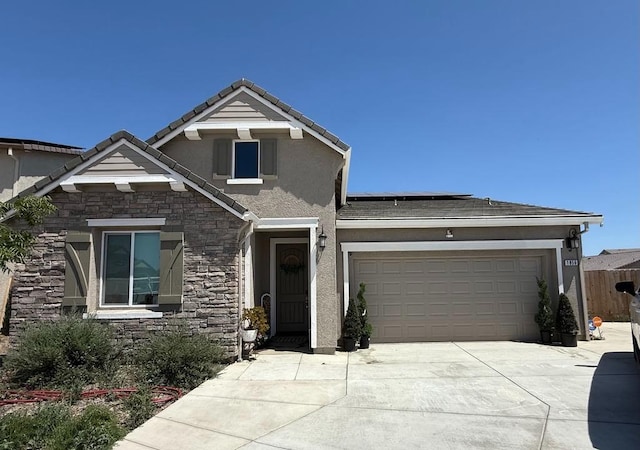 craftsman inspired home with roof mounted solar panels, concrete driveway, an attached garage, stone siding, and stucco siding