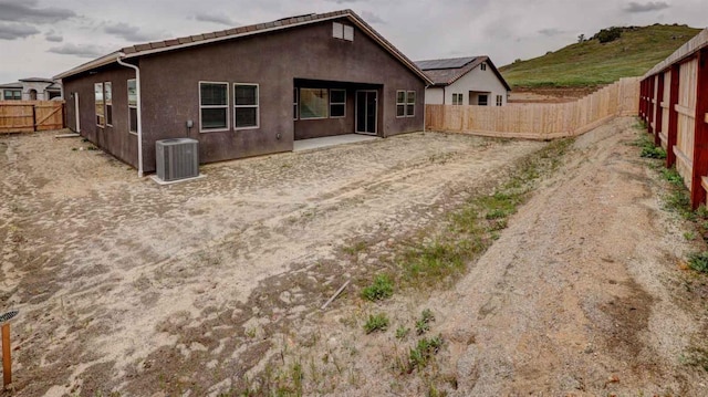 rear view of property with a patio, central AC, a fenced backyard, and stucco siding