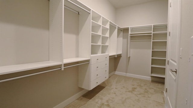 walk in closet with built in study area and light carpet