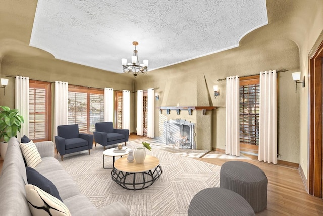 2436 N Van Ness Blvd, Fresno, CA 93704 - living area with an inviting chandelier, a textured wall, wood finished floors, a fireplace with raised hearth, and a textured ceiling