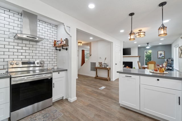 43299 Ranger Circle Dr, Coarsegold, CA 93614 - kitchen featuring decorative backsplash, dark countertops, a fireplace, stainless steel electric stove, and wall chimney exhaust hood