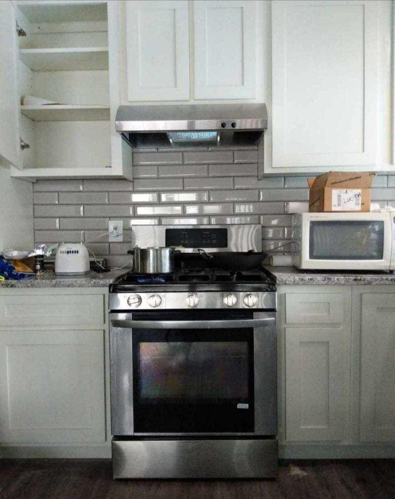 kitchen with decorative backsplash, open shelves, gas stove, white microwave, and under cabinet range hood