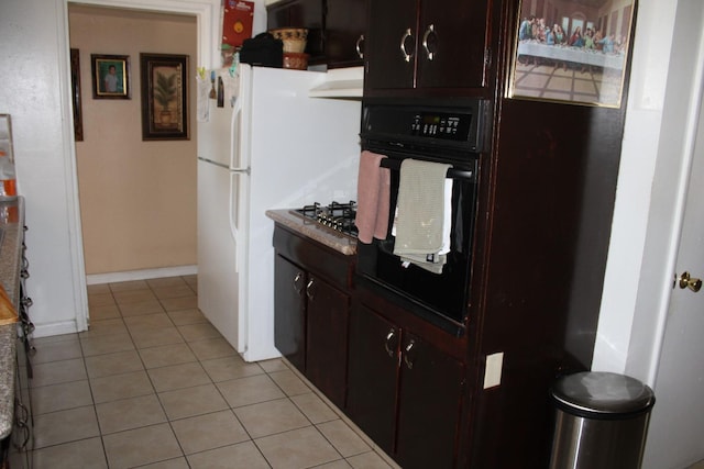 1939 S Sierra Vista Ave, Fresno, CA 93702 - kitchen featuring black oven, light tile patterned floors, dark brown cabinets, and baseboards