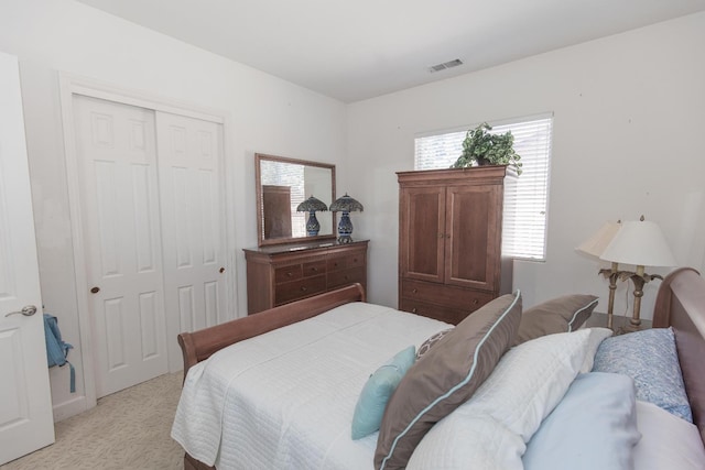 bedroom with a closet, visible vents, and light carpet