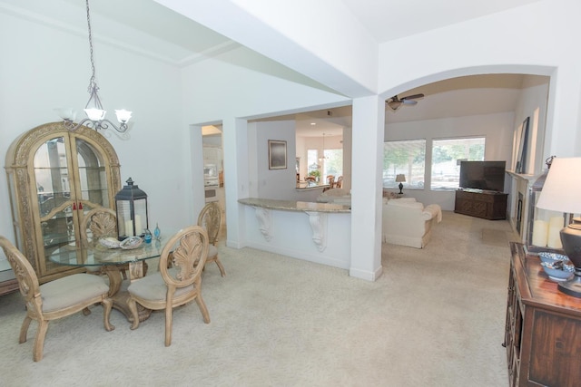 dining space with arched walkways, light colored carpet, and ceiling fan with notable chandelier