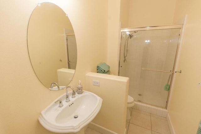 bathroom featuring toilet, tile patterned flooring, a stall shower, and a sink