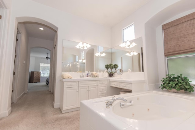 full bath featuring vanity, ceiling fan with notable chandelier, and a whirlpool tub