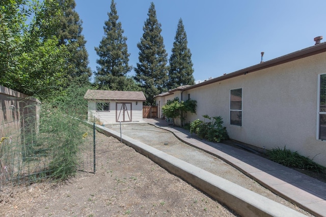 exterior space with an outdoor structure, stucco siding, fence, and a storage unit