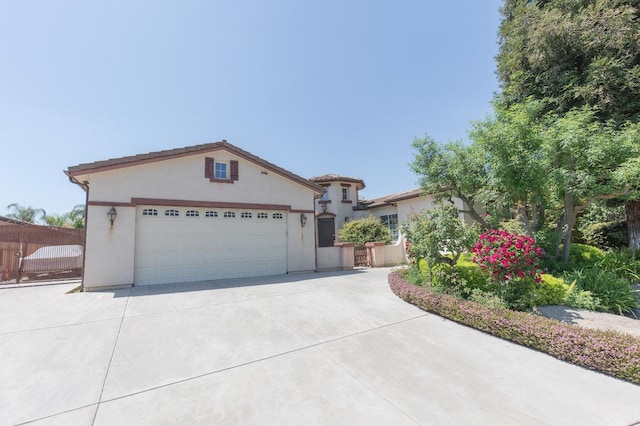 view of front of home featuring concrete driveway, stucco siding, fence, and an attached garage