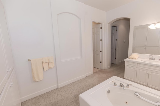 full bathroom featuring a tub with jets, vanity, and baseboards