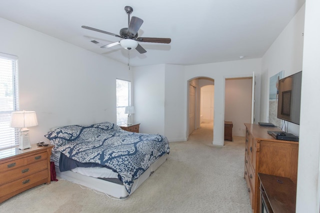 carpeted bedroom with arched walkways, ceiling fan, baseboards, and visible vents