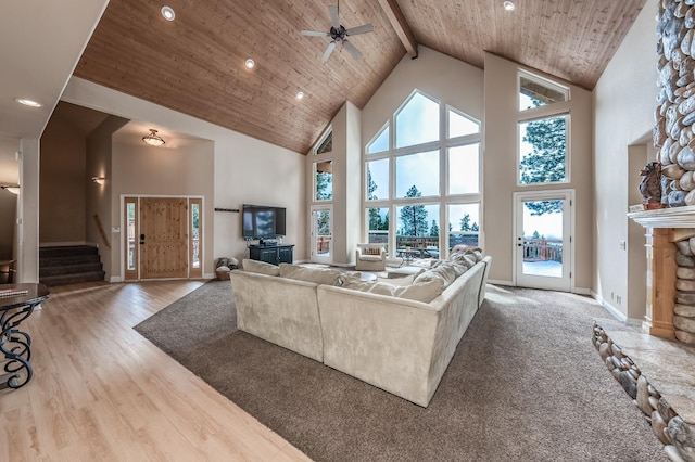 living room with wooden ceiling, a stone fireplace, high vaulted ceiling, and a healthy amount of sunlight