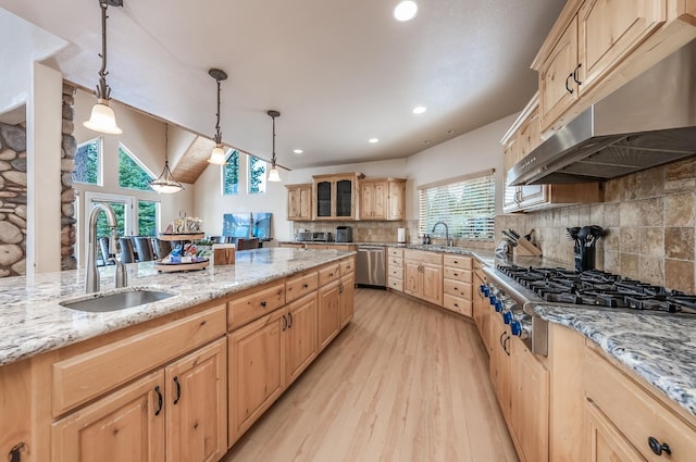 kitchen with a sink, stainless steel appliances, light brown cabinets, under cabinet range hood, and light wood-style floors