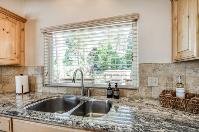 kitchen featuring a sink, light brown cabinets, stone countertops, and tasteful backsplash