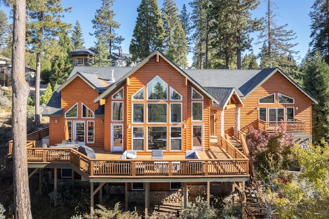 back of house featuring roof with shingles, a deck, and faux log siding