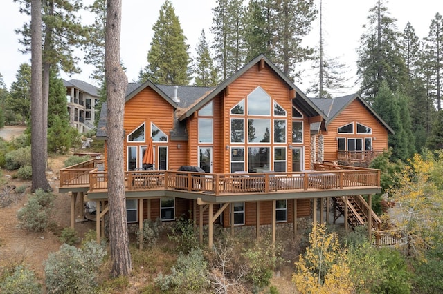 back of house featuring stone siding, log veneer siding, a deck, and stairs
