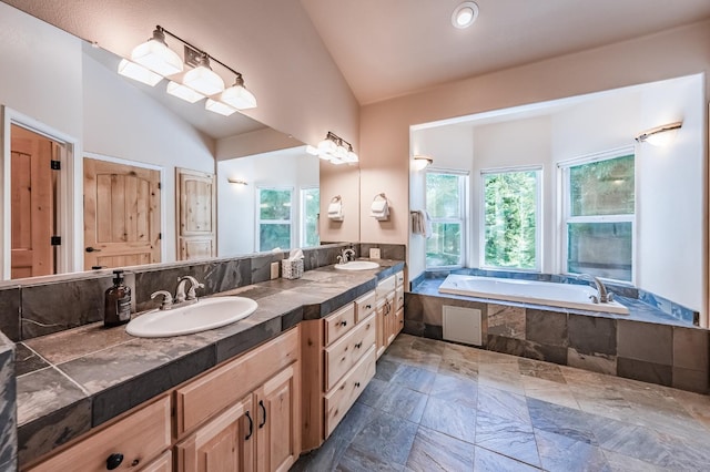 full bath featuring a wealth of natural light, a bath, a sink, and vaulted ceiling
