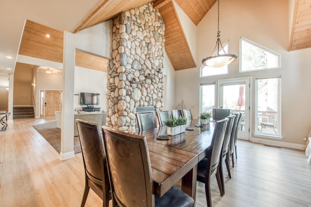 dining space with baseboards, visible vents, high vaulted ceiling, beamed ceiling, and light wood-type flooring