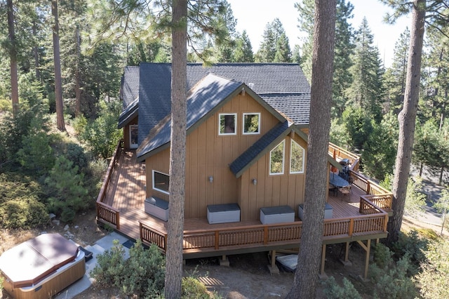 back of property featuring a hot tub, roof with shingles, and a deck