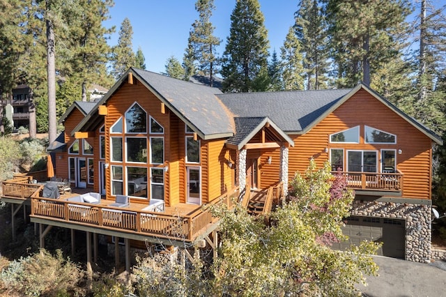 view of front of property featuring a deck, roof with shingles, a garage, and aphalt driveway