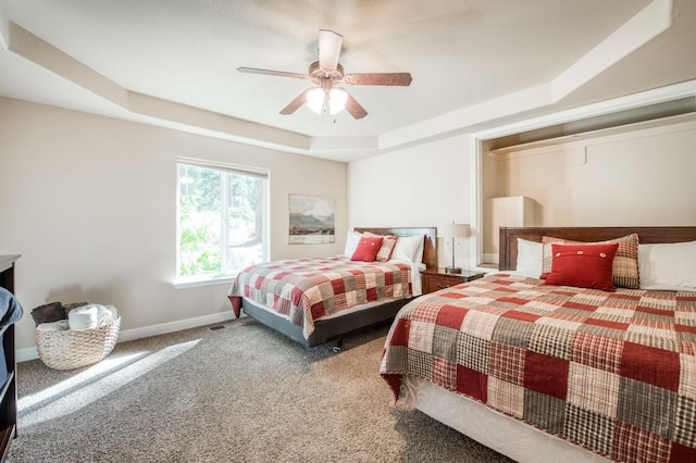 bedroom featuring a tray ceiling, carpet, baseboards, and a ceiling fan