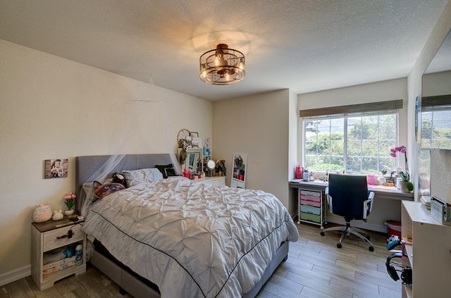 bedroom featuring a textured ceiling, wood finished floors, and multiple windows