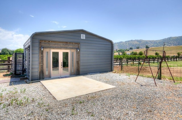 rear view of property featuring an outbuilding, a mountain view, and fence
