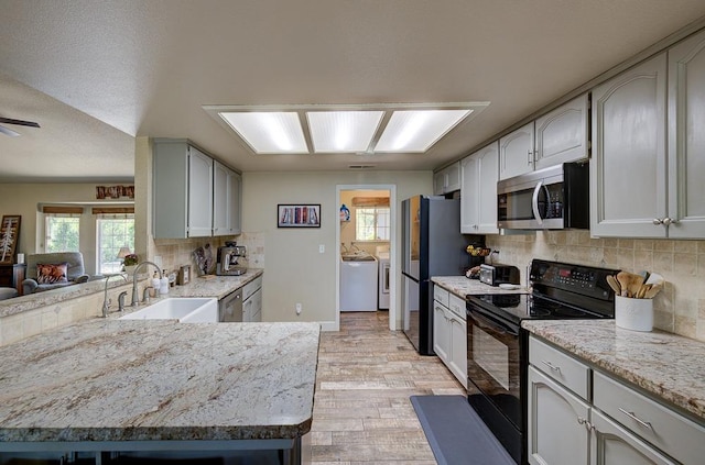 20794 E Weldon Ave, Sanger, CA 93657 - kitchen featuring stainless steel appliances, separate washer and dryer, light wood-style floors, a peninsula, and tasteful backsplash