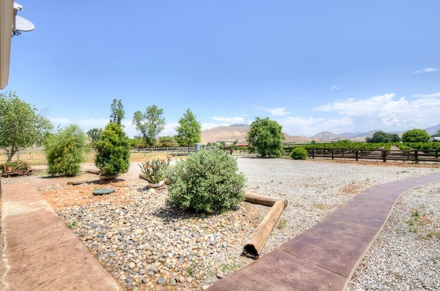 view of yard with fence, a rural view, and a mountain view