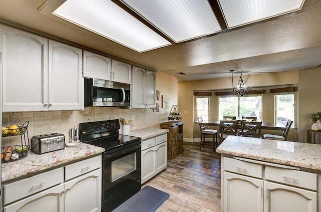 20794 E Weldon Ave, Sanger, CA 93657 - kitchen featuring stainless steel microwave, black electric range oven, backsplash, hanging light fixtures, and wood finished floors