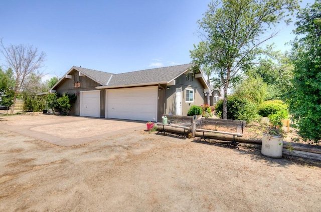 view of front facade featuring roof with shingles, driveway, fence, and a garage