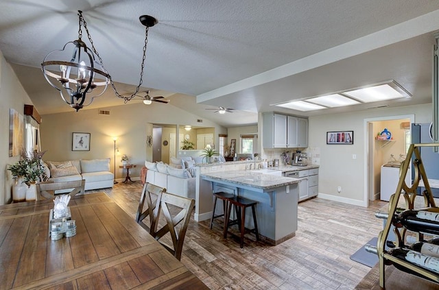 kitchen featuring a breakfast bar, a peninsula, light wood-style flooring, and open floor plan