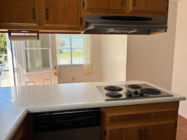 kitchen with stainless steel dishwasher, electric cooktop, light countertops, and under cabinet range hood