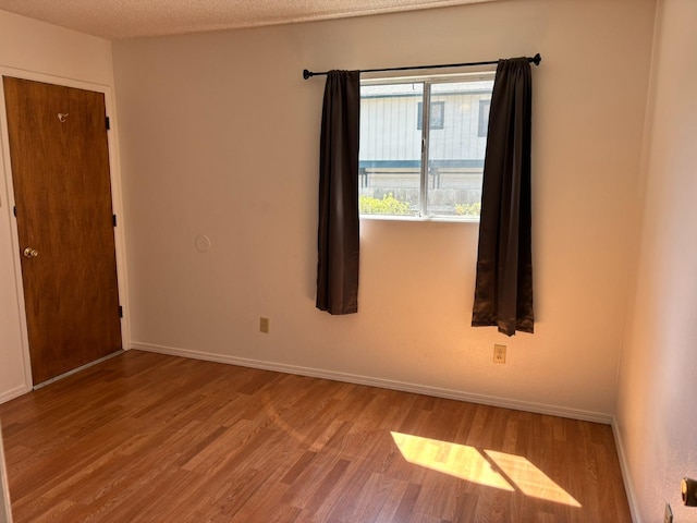 spare room featuring wood finished floors and baseboards