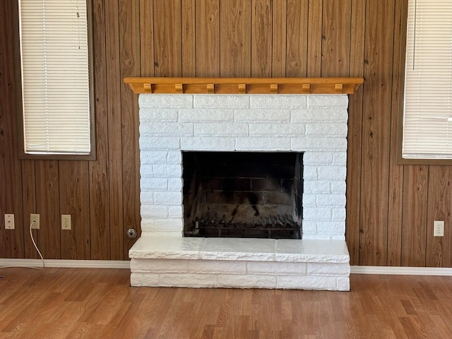 interior details with wooden walls, baseboards, a fireplace with raised hearth, and wood finished floors