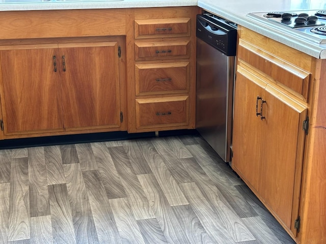 room details featuring light countertops, appliances with stainless steel finishes, brown cabinetry, and wood finished floors