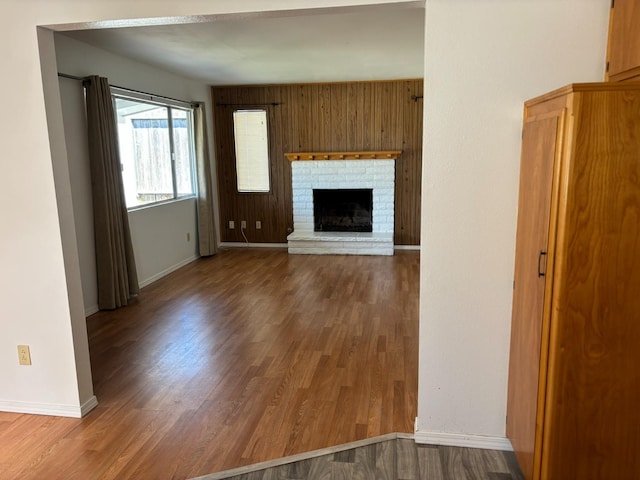 unfurnished living room with wood finished floors, baseboards, and a fireplace
