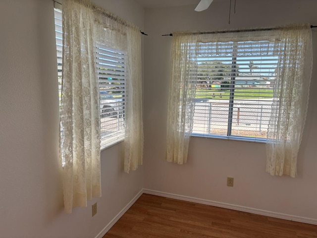 empty room with a wealth of natural light, baseboards, and wood finished floors