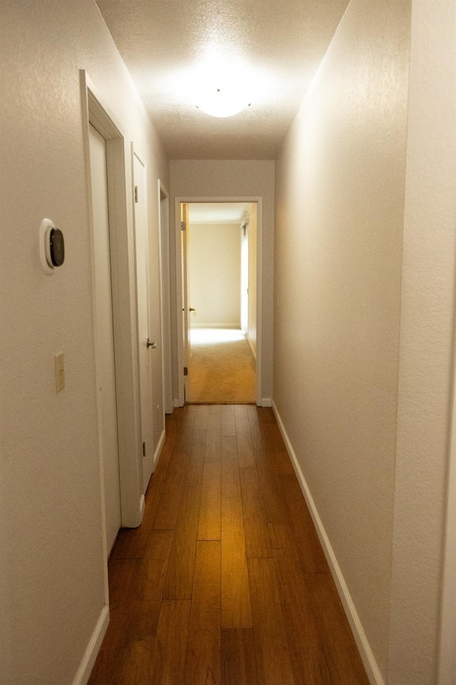 hallway with baseboards and wood-type flooring