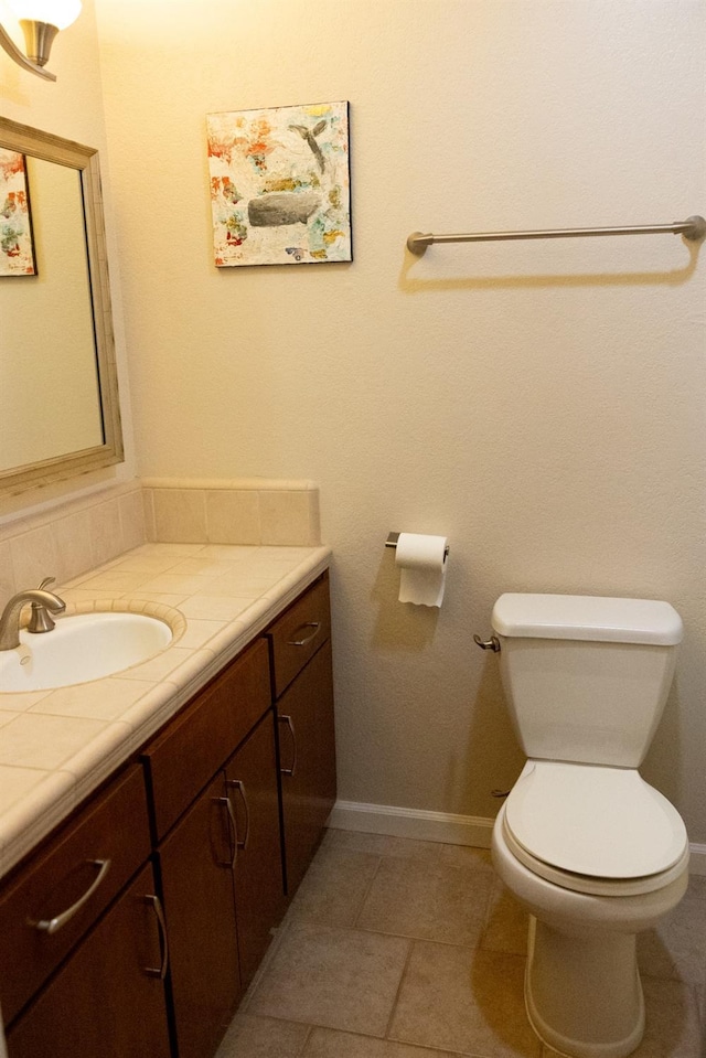 bathroom featuring toilet, baseboards, tile patterned flooring, vanity, and backsplash