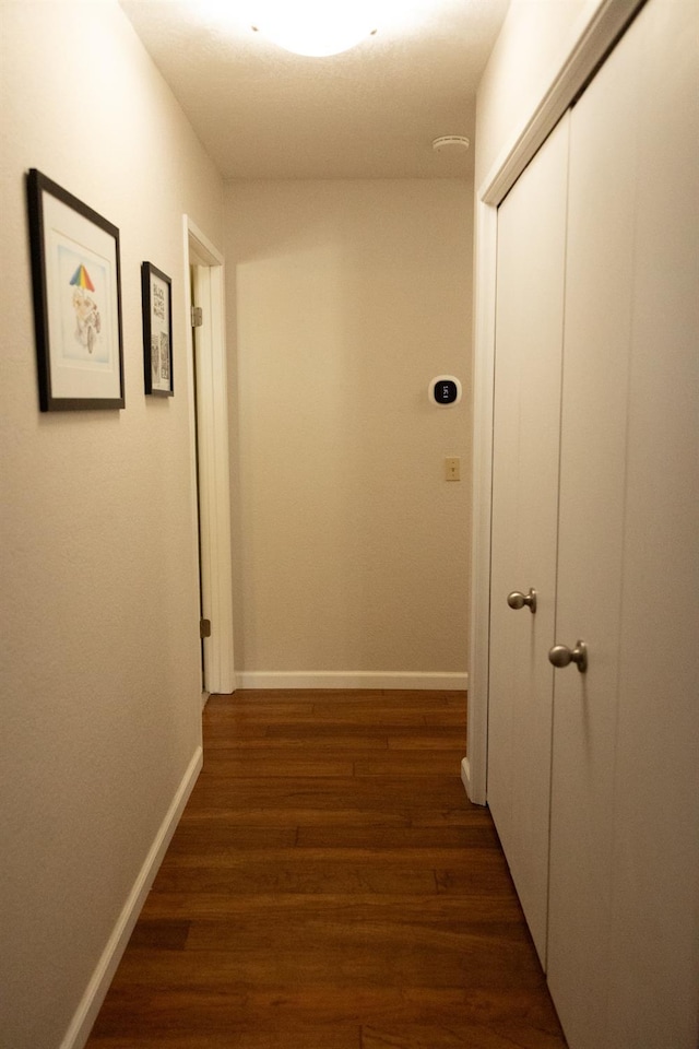 corridor with dark wood finished floors and baseboards